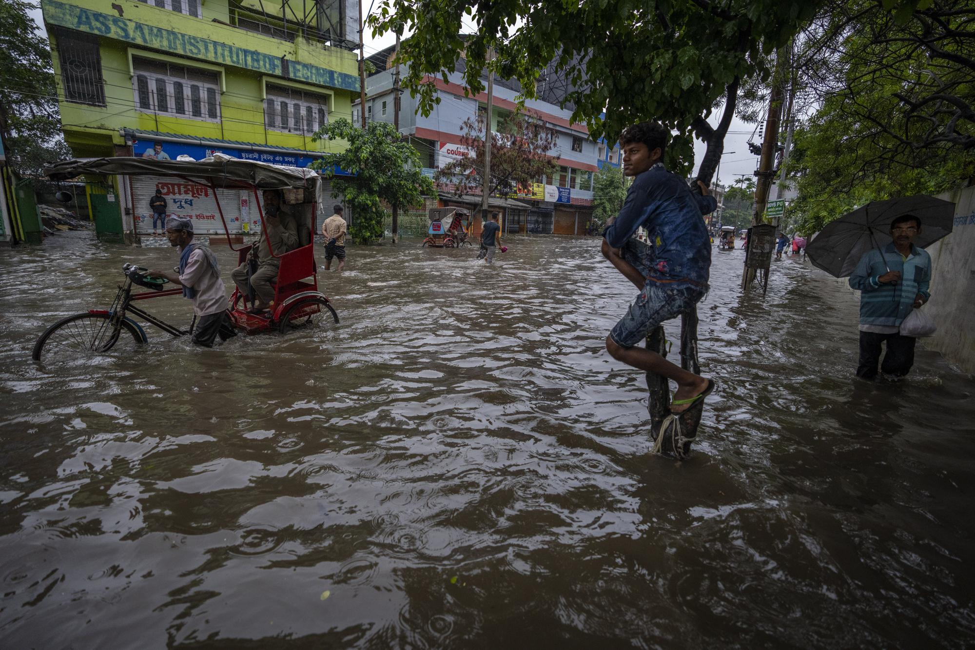 13. People wade through a flooded road after heavy rains in Gauhati, Assam state, India, on June 14, 2022.