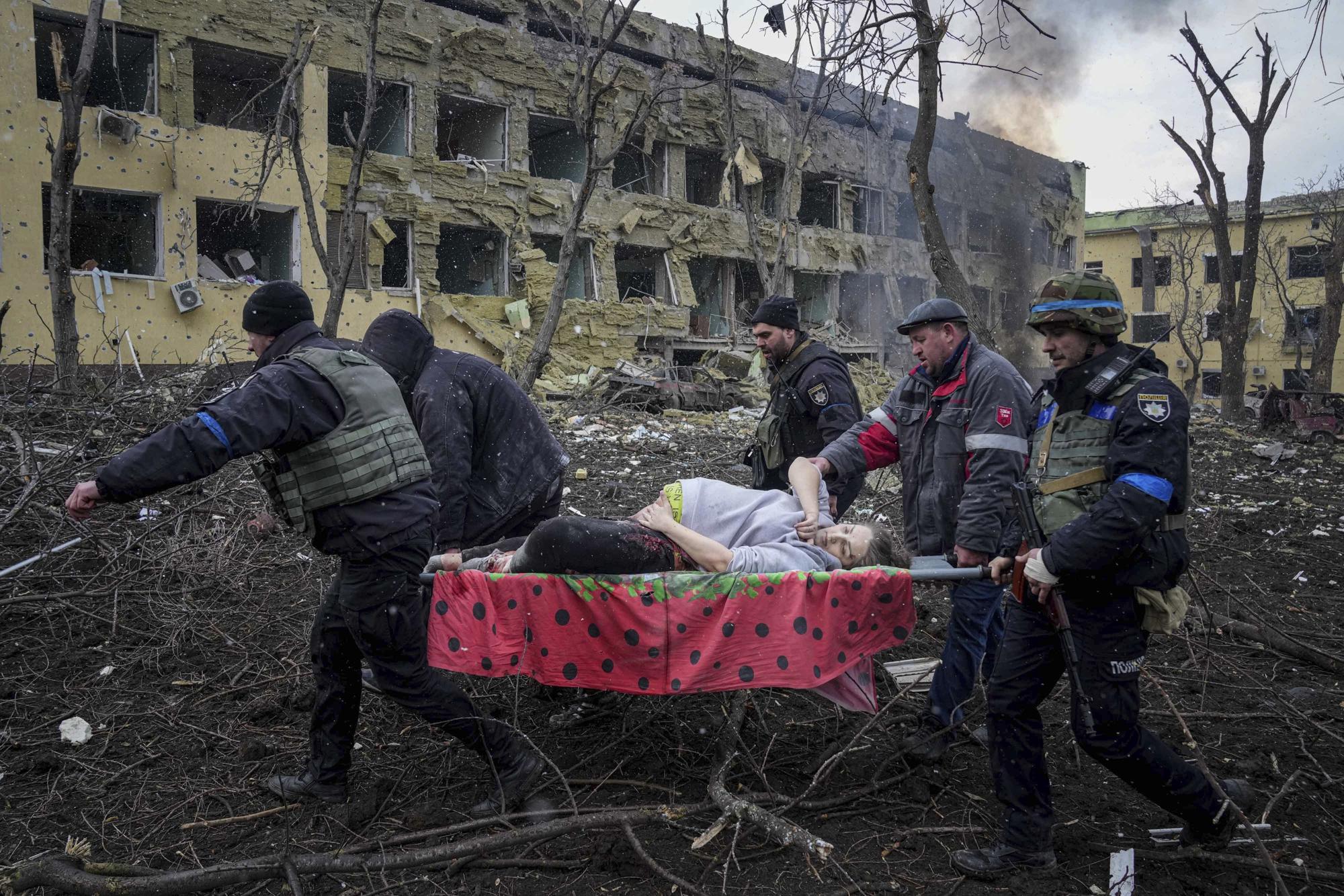 6. Ukranian emergency workers and volunteers carry an injured pregnant woman from a maternity hospital damaged by an airstrike in Mariupol, Ukraine, on March 9, 2022. The woman was taken to another hospital but did not survive.