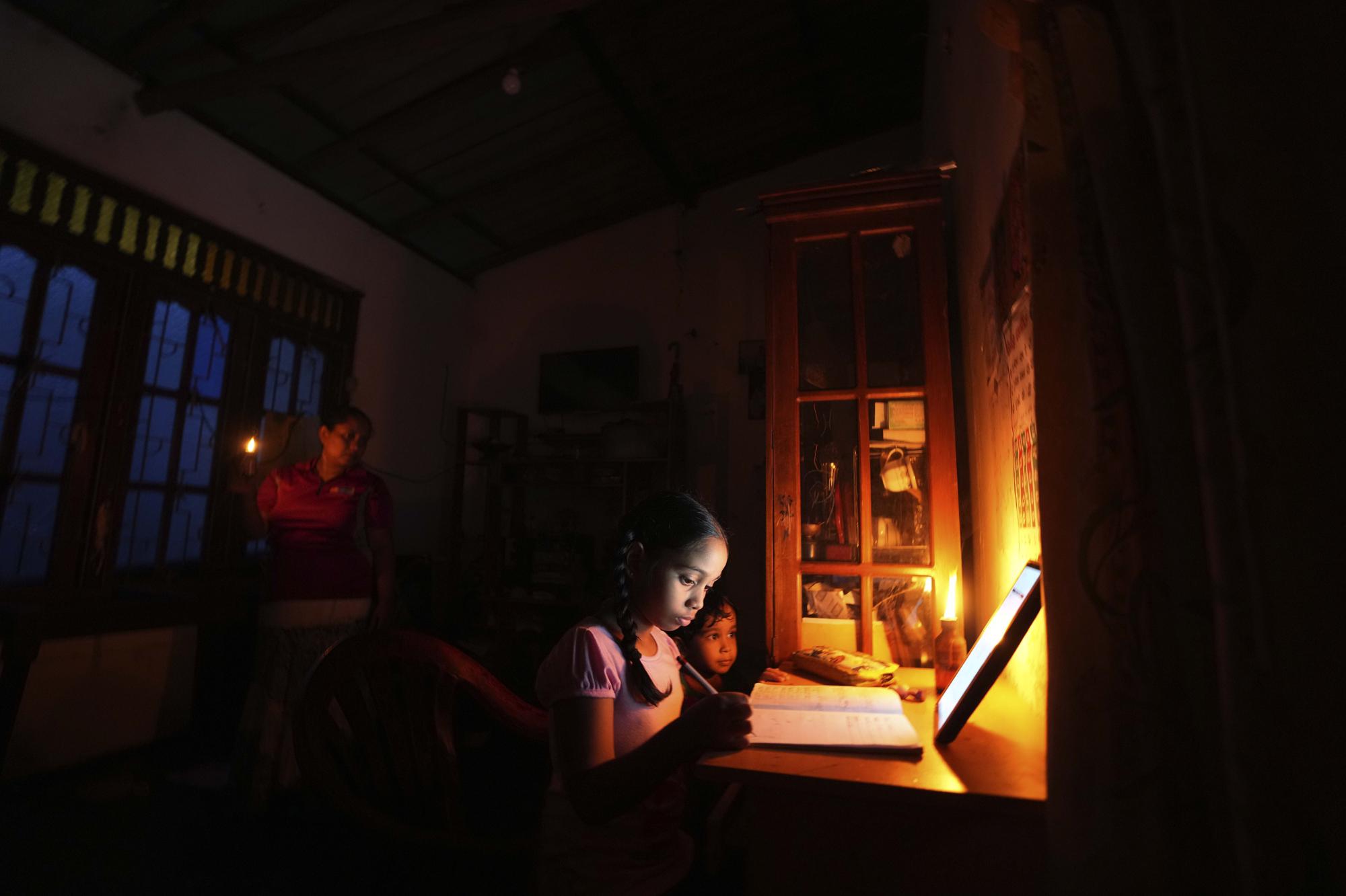 7. A girl uses a kerosine oil lamp to attend online lessons during a power cut brought on by a fuel shortage in Colombo, Sri Lanka, on March 4, 2022.