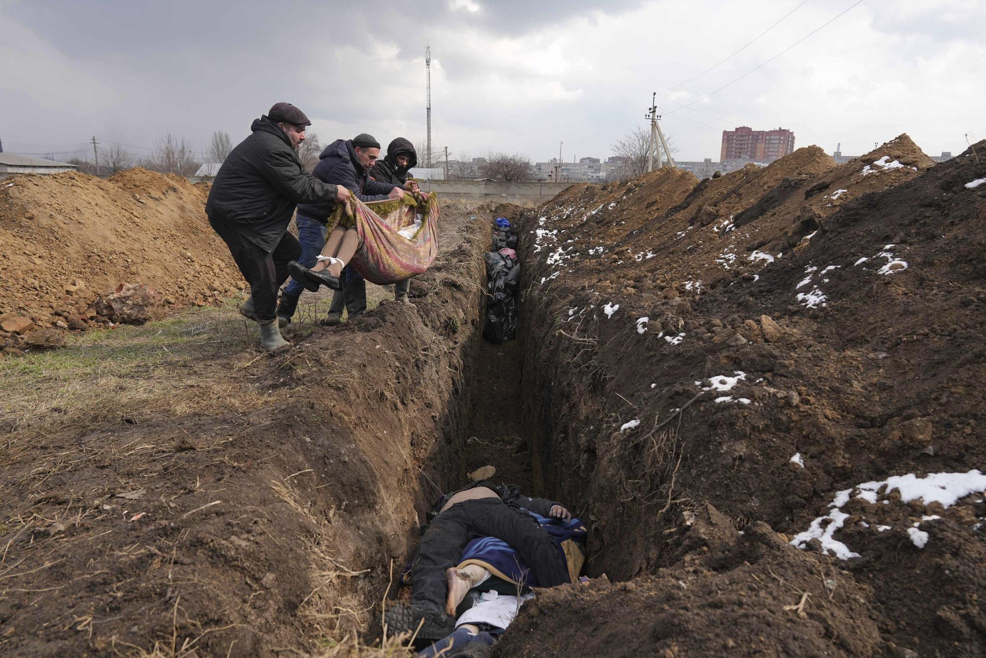 9. Bodies are lowered into a mass grave on the outskirts of Mariupol, Ukraine, on March 9, 2022, as people cannot bury their dead because of the heavy shelling by Russian forces.
